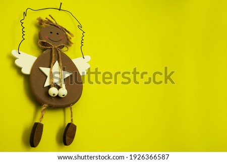 brown wooden guardian angel hanging on a small nail on a green wall side view