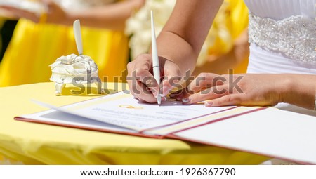 Hands of a young woman, bride, sign the marriage document. Wedding ceremony. 