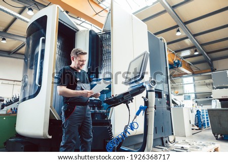 Worker in metal industry operating a modern cnc lathe Royalty-Free Stock Photo #1926368717