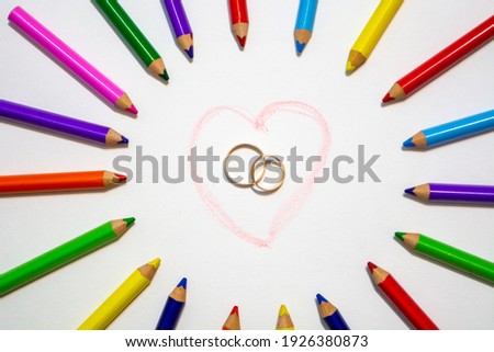 Heart and rings in a circle of colored pencils