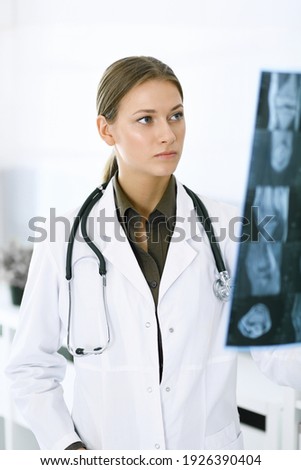 Woman-doctor examining x-ray picture in hospital. Surgeon or orthopedist at work in clinic. Medicine and healthcare concept