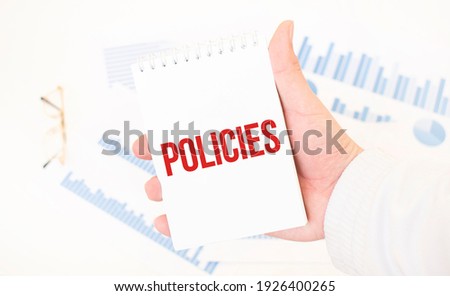 Businessman holding a white notepad with text POLICIES, business concept
