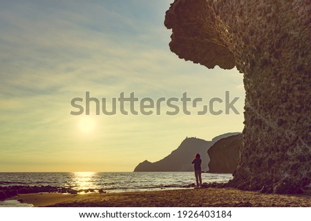 Tourist woman with camera taking travel picture on Monsul beach. Cabo de Gata Nijar Natural Park, province Almeria, Andalusia, Spain.