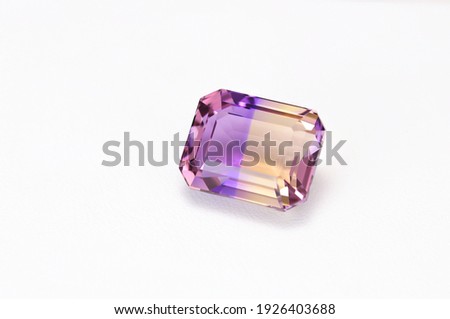 Loose natural bicolor: purple and yellow, Bolivian ametrine emerald cut faceted gemstone on white leather textured background Royalty-Free Stock Photo #1926403688