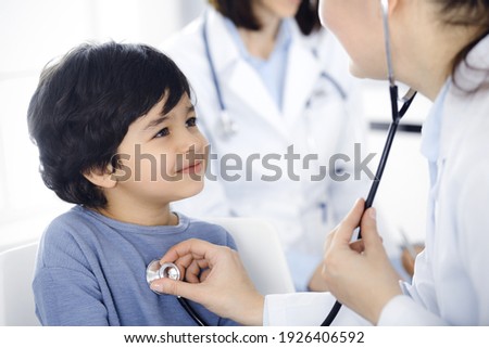 Doctor-woman examining a child patient by stethoscope. Cute arab boy at physician appointment. Medicine concept Royalty-Free Stock Photo #1926406592