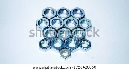 On a white background, close-up are metric nuts of different sizes, for fastening bolts and threaded rods.