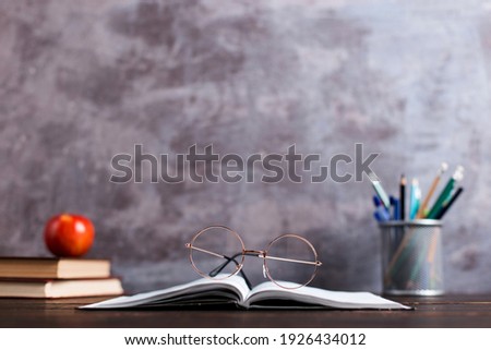 Concept to teacher's day. Pens, apple, pencils, books and glasses on table. Back to school, copy space.