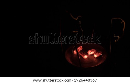 Close-up of burning charcoal cubes. Action. Cubes of embers burning in bowl for smoking hookah. Creative artwork decoration on dark background. Empty space. Selective focus