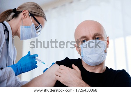 Young female doctor giving injection to patient.