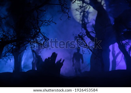bloodthirsty zombies attacking concept. Silhouette of scary zombie walking in the dead forest at night. Creative table decorations. Selective focus