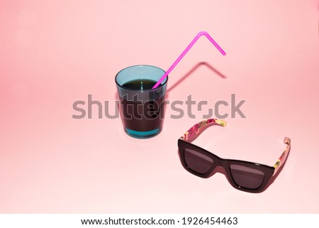 Sunglasses and soda with pink straw on pink background. Spring and summer ambient. 