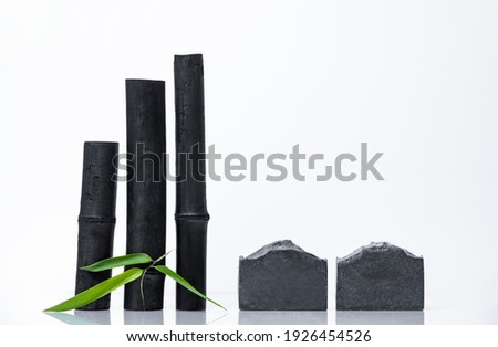 Bamboo activated charcoal sticks, green leaf and handmade soap with coal on white background