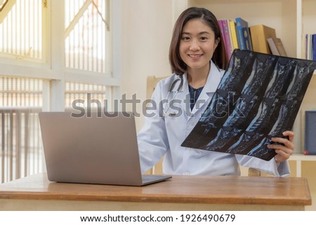 Warm tone.Female doctor working with laptop and shown the MRI result in spine patient.Selective focus with blur background.Woman with white medical gown suit sitting at modern private hospital.