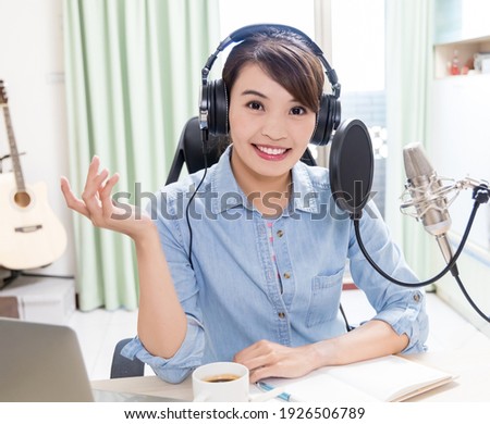 asian woman with headphones and microphone recording podcast at studio
