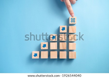 Businessman's hand arranging wooden blocks staircase with arrow icon, Business planning concept.