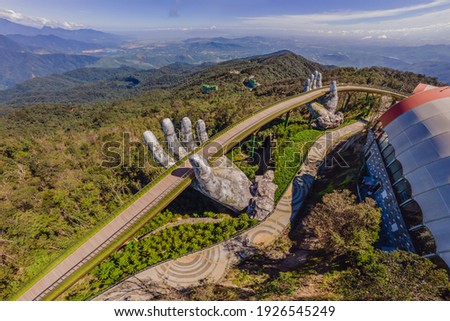 Top aerial view of the famous Golden Bridge is lifted by two giant hands in the tourist resort on Ba Na Hill in Da Nang, Vietnam Royalty-Free Stock Photo #1926545249