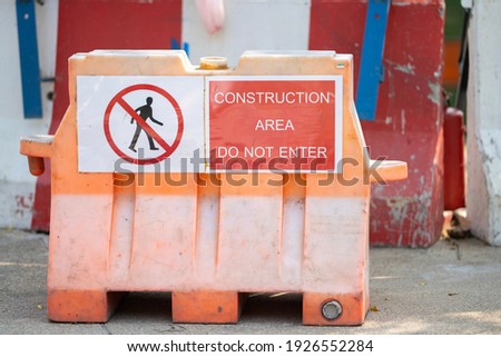 Warning sign not to enter the construction area on plastic jersey barriers.