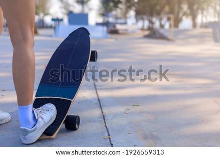 Close-up Asian women surf skate or skateboard outdoors on beautiful morning. Happy young women play surf skate at ramp park on morning time. Close up Asian women leg wear sneaker play surf skate  Royalty-Free Stock Photo #1926559313