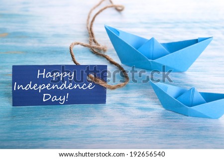 A Blue Tag with Happy Independence Day and Boats in the Background