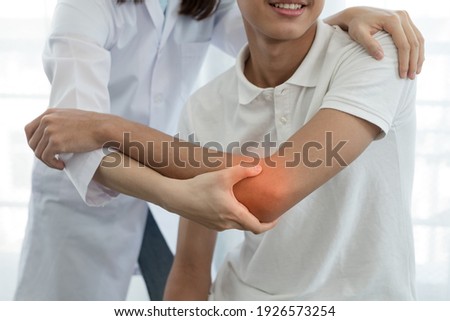 Female physiotherapists provide assistance to male patients with elbow injuries examine patients in rehabilitation centers. Rehabilitation physiotherapy concept. Royalty-Free Stock Photo #1926573254