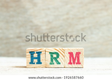 Alphabet letter block in word HRM (Abbreviation of human resource management) on wood background