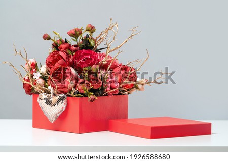 Red gift box of rich rose flowers bouquet with golden branches and heart. Mothers or International Women's Day, 8 March, 14 February, St Valentines Day greeting card. Wedding and thank you. Copy space