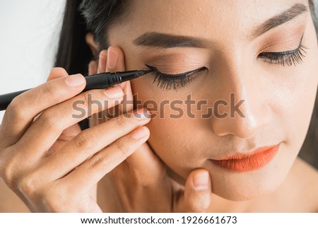 mixed race asian woman putting eye liner on eyelid on white background Royalty-Free Stock Photo #1926661673