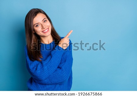 Photo of young beautiful smiling good mood positive girl pointing finger in copyspace isolated on blue color background