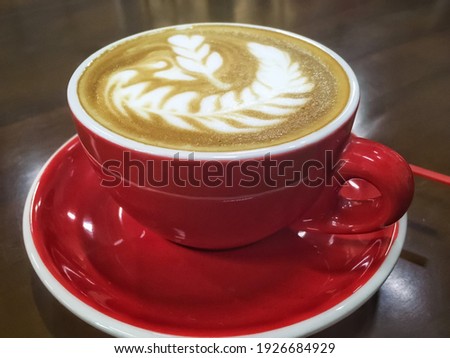 Coffee in red cup on wooden table in cafe with lighting background