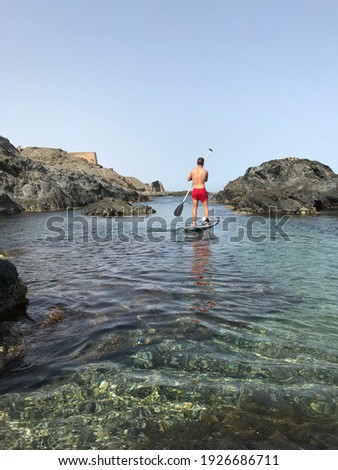Young boy paddling down a rocky beach