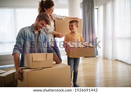 Happy family unpacking boxes in new home on moving day Royalty-Free Stock Photo #1926691442