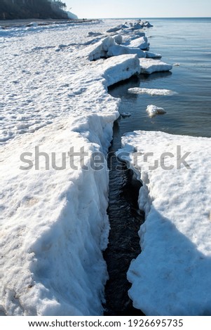 Winter seaside landscape, melting ice and snow on the beach.