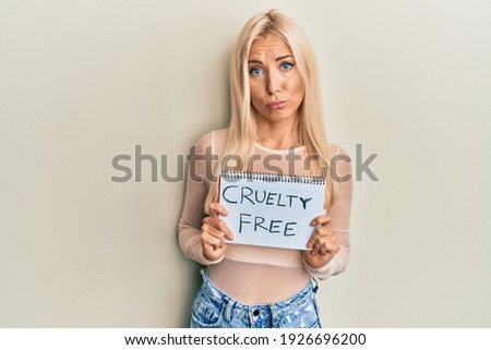 Young blonde woman holding cruelty free message banner depressed and worry for distress, crying angry and afraid. sad expression. 