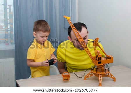 Сoncept of people-a happy father and young son play. Happy family son and loving young father spend leisure time together, play, build toy crane. Selective Focus.