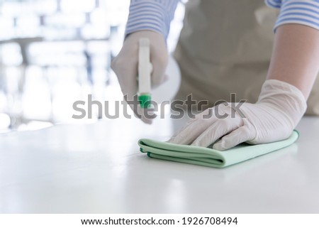 Close up Staff hand Restaurant workers are cleaning table and spraying disinfectants during the virus outbreak, Using cleaning solutions or using alcohol to kill germs in the restaurant. Royalty-Free Stock Photo #1926708494