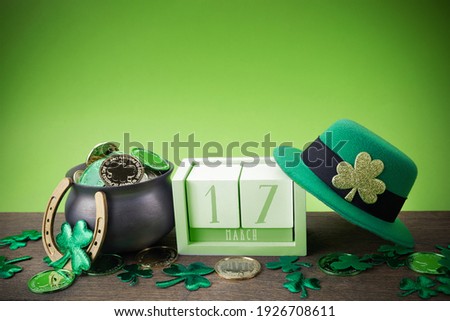 Happy St. Patrick's day. Shiny shamrocks, gold coins and leprechaun hat on a wooden background
