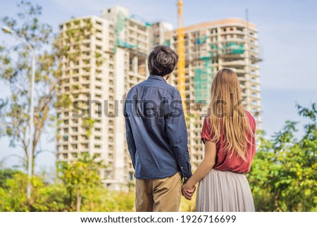 Couple looking at their new house under construction, planning future and dreaming. Young family dreaming about a new home. Real estate concept Royalty-Free Stock Photo #1926716699