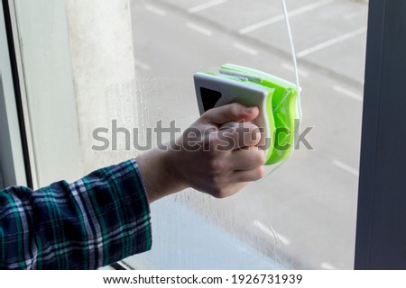 Man's hand washing and cleaning the window. Wash the window with a magnetic brush. Simultaneous window cleaning on both sides. Glass cleaner. Royalty-Free Stock Photo #1926731939