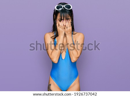Young hispanic woman wearing swimsuit and sunglasses rubbing eyes for fatigue and headache, sleepy and tired expression. vision problem 