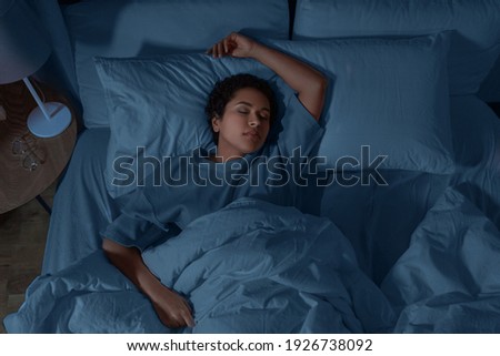 people, relax and comfort concept - young african american woman sleeping in bed at home at night Royalty-Free Stock Photo #1926738092