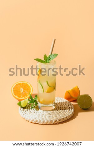 Cold and refreshing lemonade or cocktail with orange and lime slice on color background. Summer drink. Royalty-Free Stock Photo #1926742007