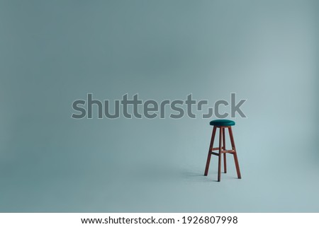Bar stool with upholstered backless seat in an empty white room on a gray background. Royalty-Free Stock Photo #1926807998