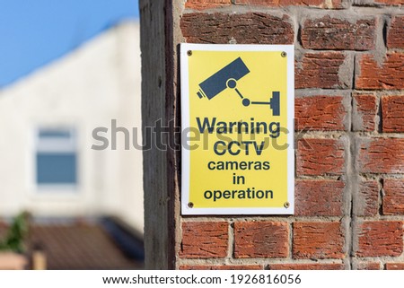 A CCTV warning sign on a brick wall outside a house