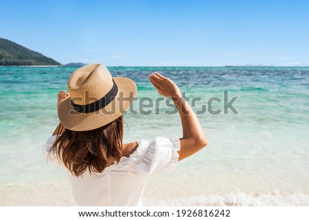 Young woman traveler wearing sunglasses covering face by hand to protect UV rays from the sun at tropical sandy beach on sunny day, Skin care and eyes protect concept Royalty-Free Stock Photo #1926816242