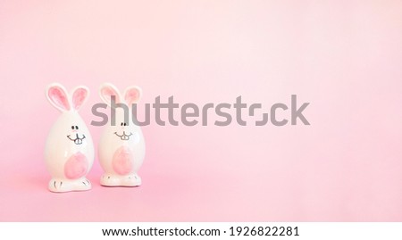 Cute white ceramic easter bunnies or rabbits on pink background. Minimal Holiday concept. Symbol Happy Easter holiday. Creative. Copy space