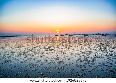 fantastic colorful landscape of a beach low tide, overcast clouds glowing in sunlight at sunset over the coastline. picturesque view. color in nature. natural creative picture