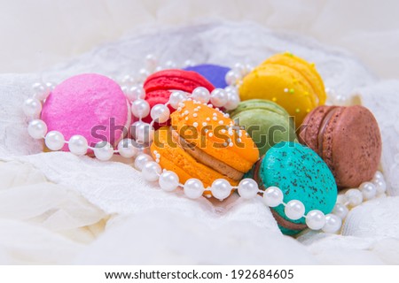 Colorful macarons on white lace and pearl necklace