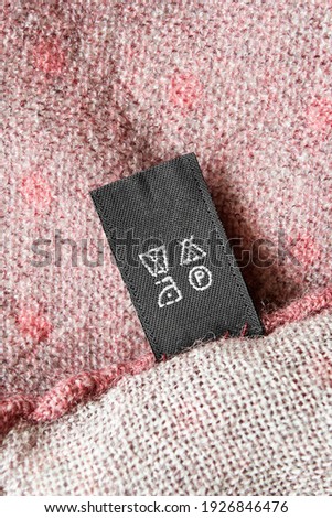 Care instructions clothing label on wool pink background