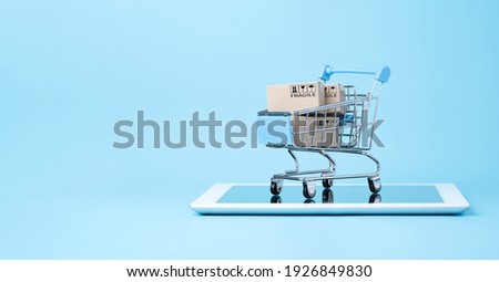 Isolated of Shipping paper boxes inside blue shopping cart trolley on tablet with blue background and copy space , Online shopping and e-commerce concept. Royalty-Free Stock Photo #1926849830