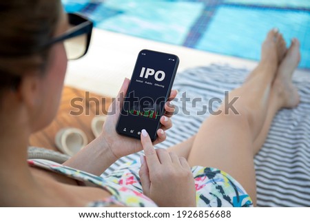 woman background pool holds phone with IPO stocks purchase app on the screen 